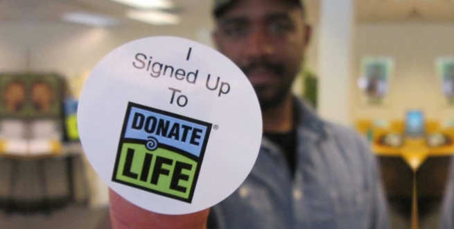 a man holding a sticker that says I signed up to donate life