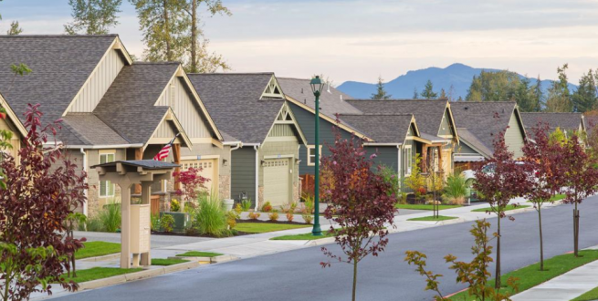 Image of subdivision with green street lights and red trees.