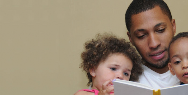 Man reading a book to two children.