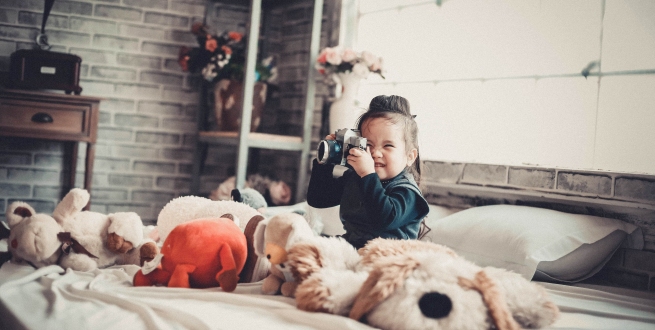 Child in a bed taking a photograph