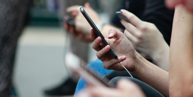 A line of people sitting looking at their phones